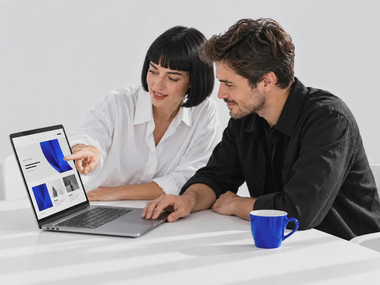 Zwei Personen stimmen gemeinsam eine Website am Laptop ab